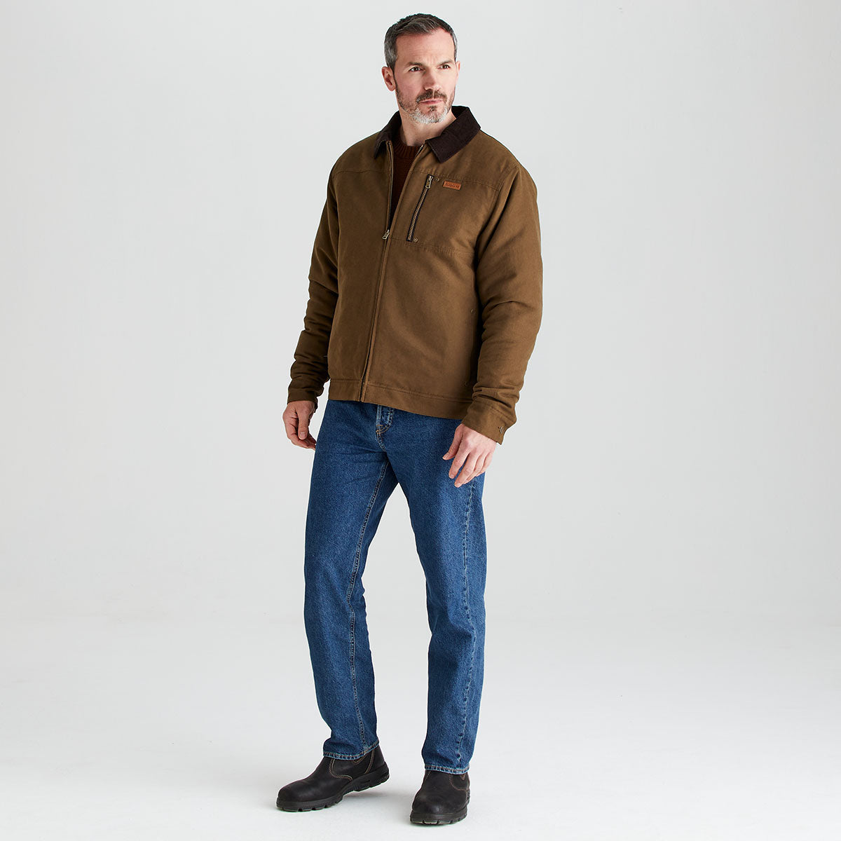 Man wearing a brown jacket and blue jeans on a white background