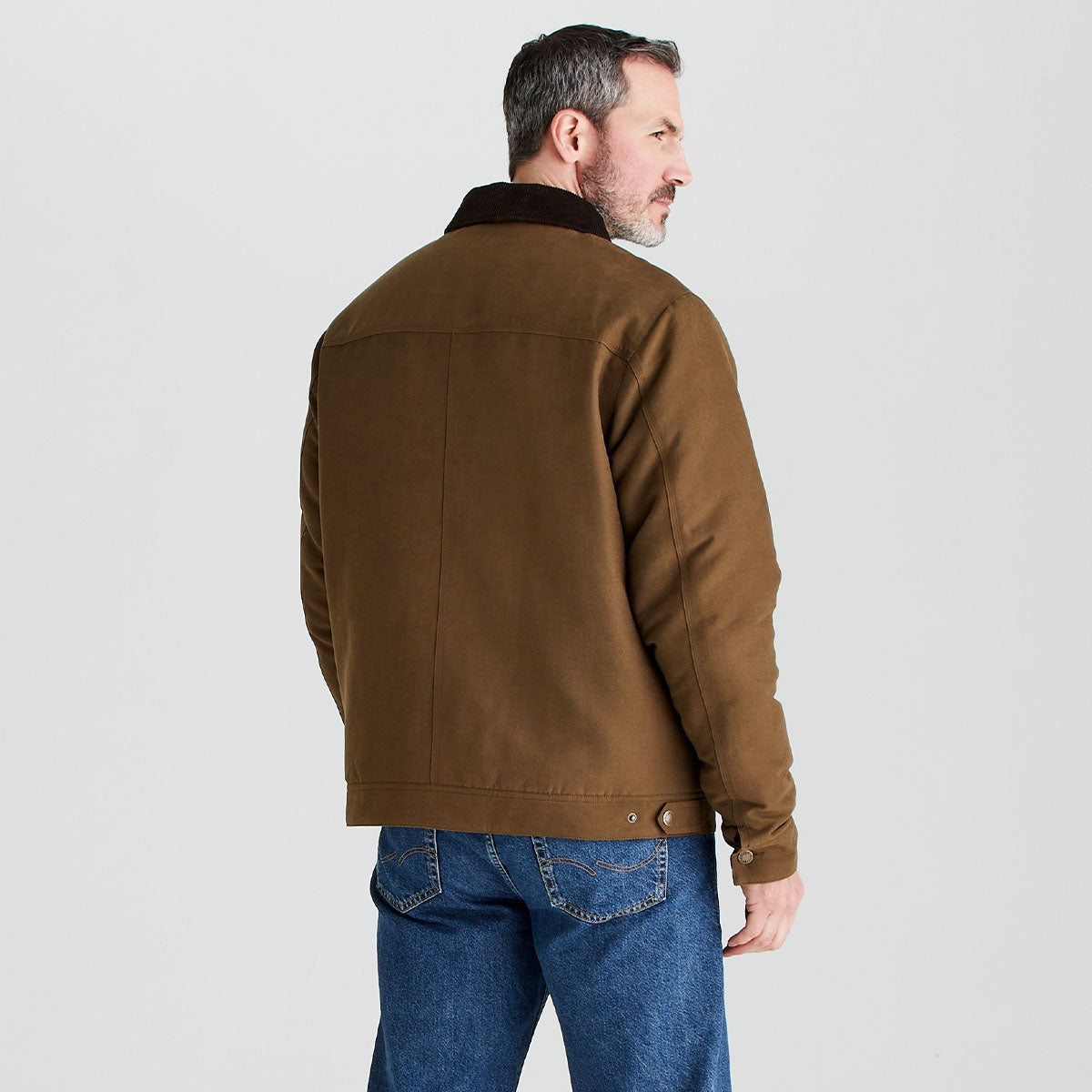 Man wearing a brown jacket and blue jeans on a light gray background