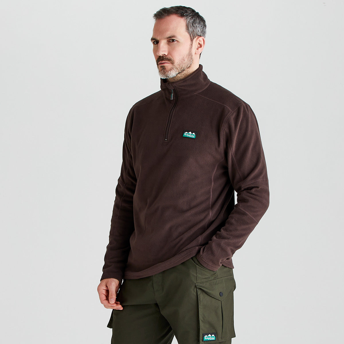 Man wearing a brown fleece pullover with a logo on a light gray background