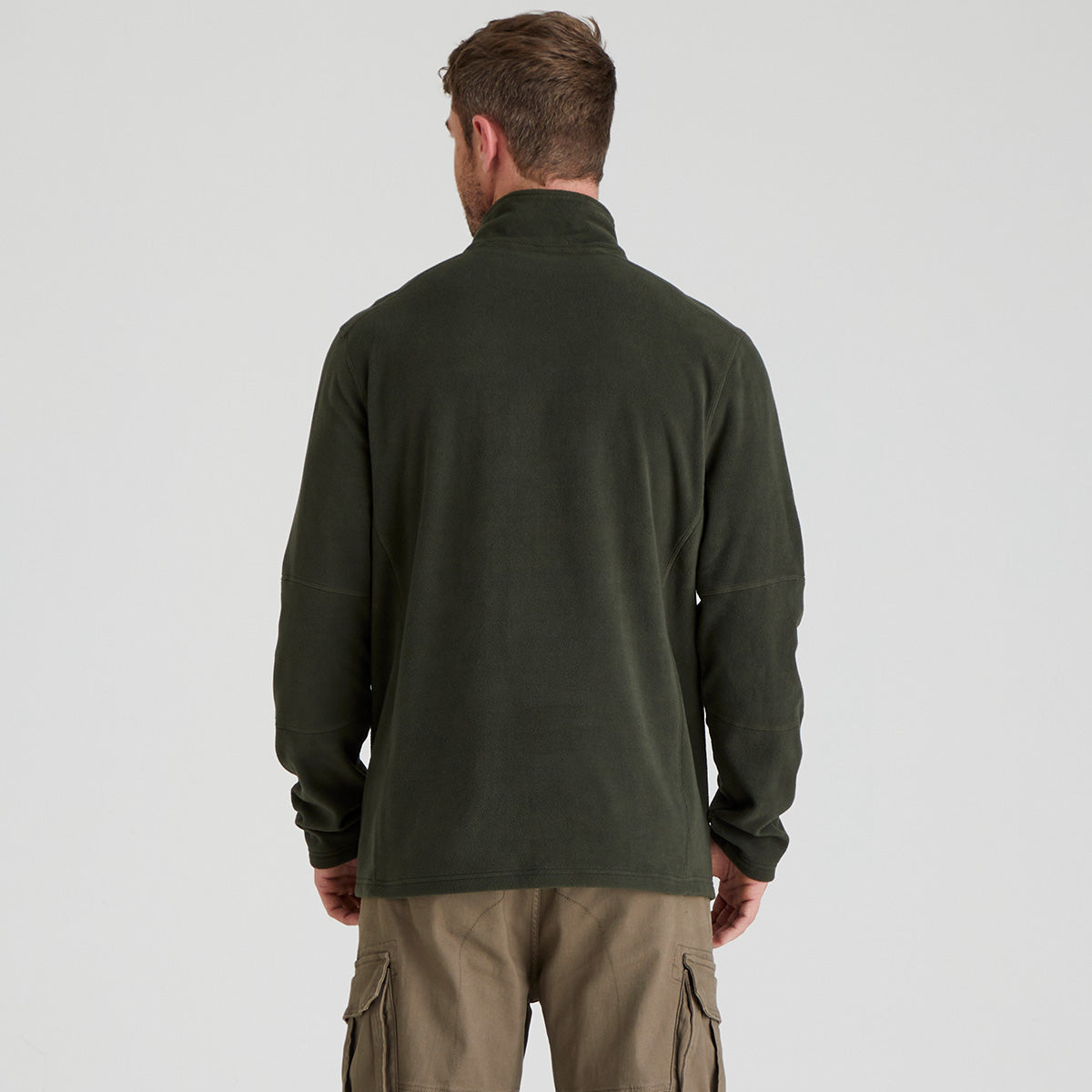 back view of man wearing a green fleece pullover and cargo pants on a light grey background