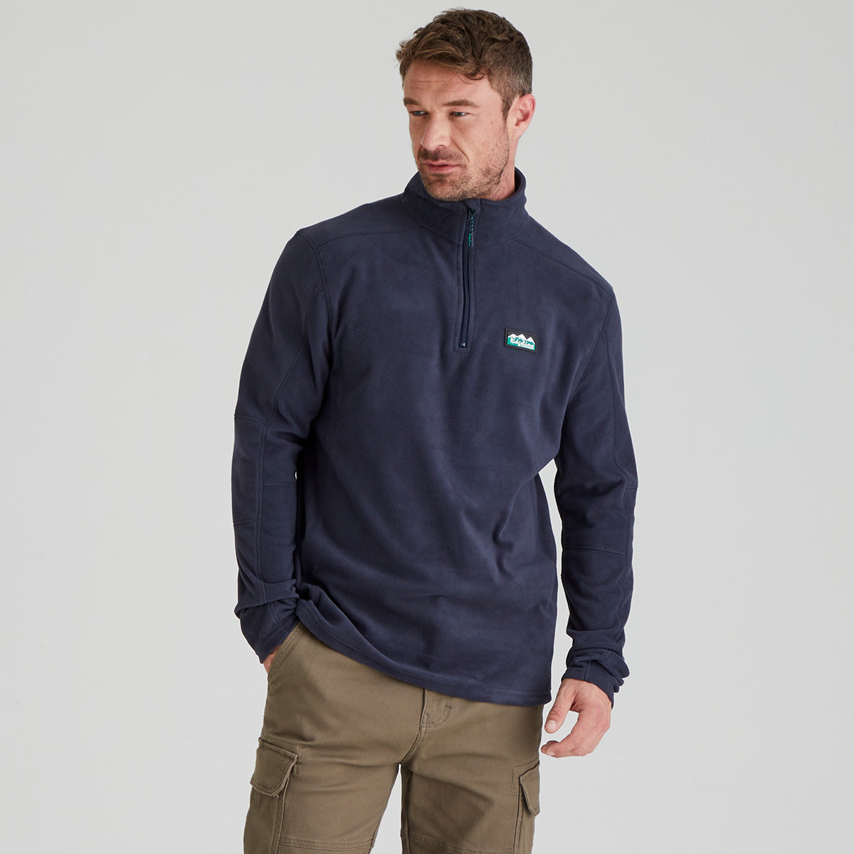 Man wearing navy fleece pullover with quarter zip. With ridgeline clothing logo