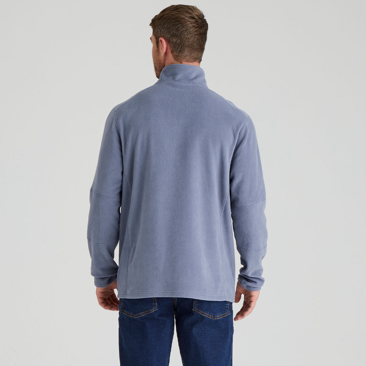 back view of man wearing a light blue long-sleeve pullover fleece on a grey background