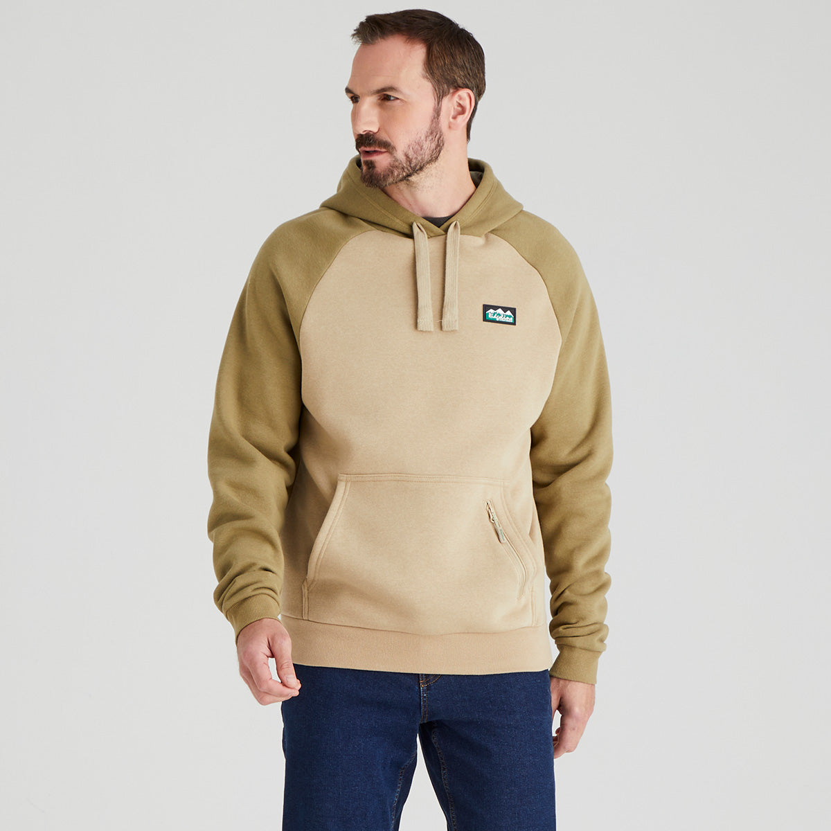Man wearing a beige and brown hoodie with a visible ridgeline clothing brand logo on a light grey background