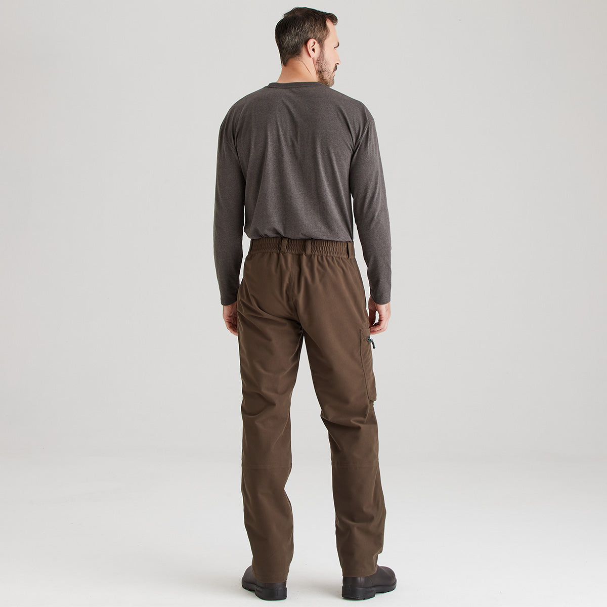 Man wearing brown pants and a gray shirt on a white background