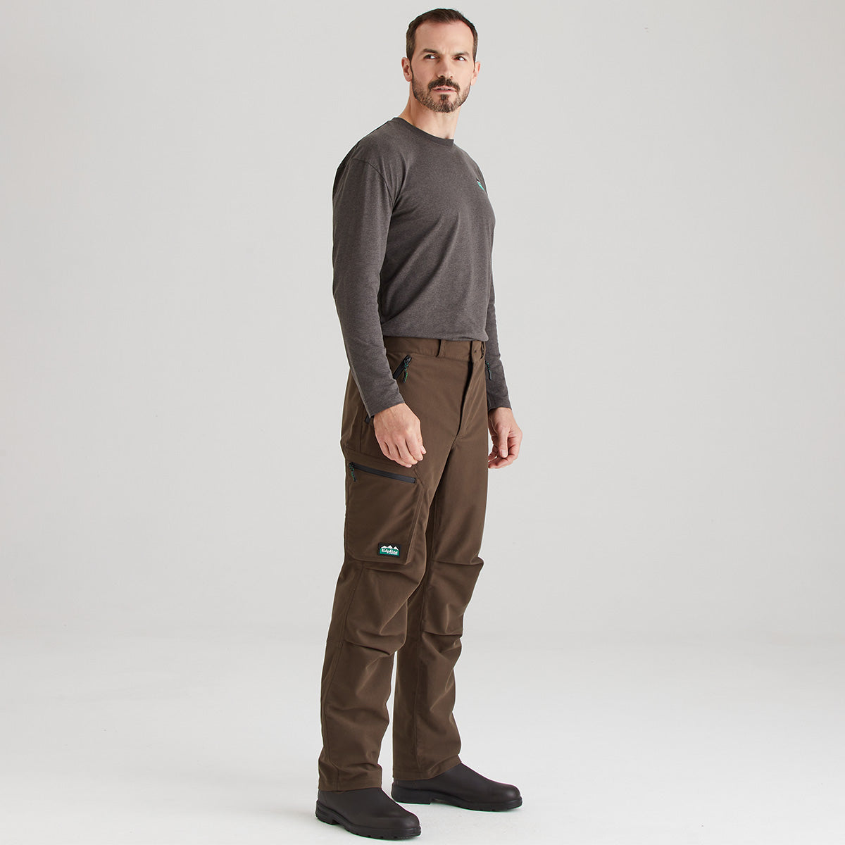 Man wearing brown pants and a gray shirt on a white background