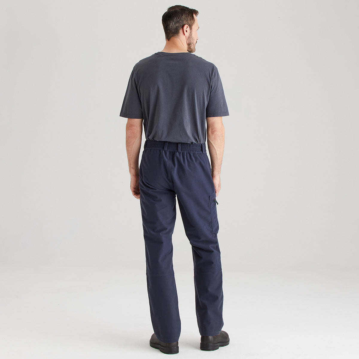 Man wearing a navy blue jumpsuit on a light gray background