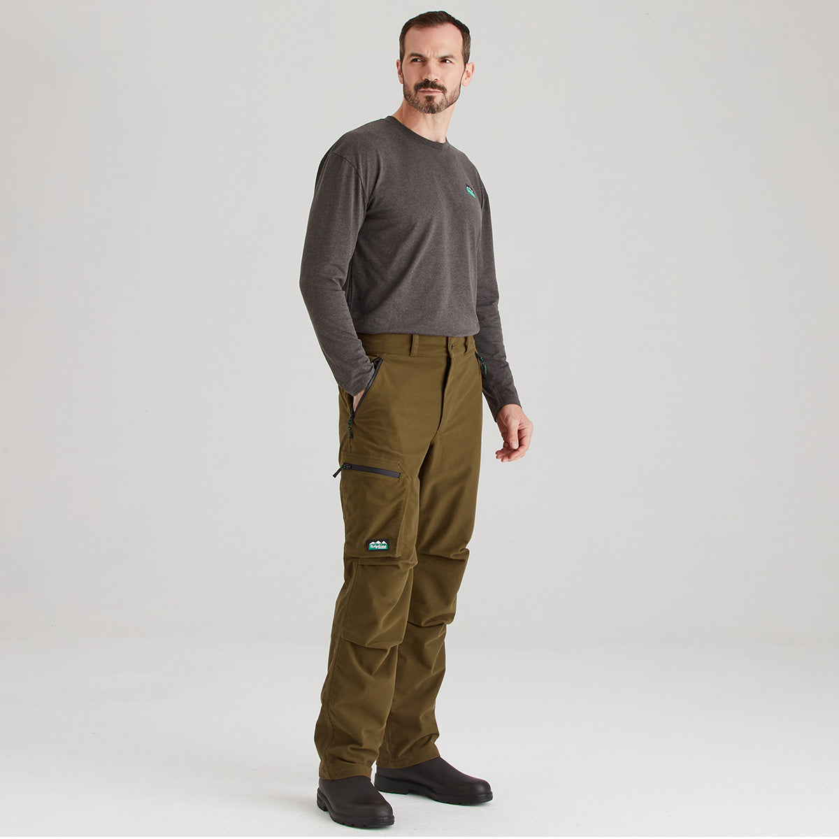 Man wearing brown pants and a gray shirt on a white background