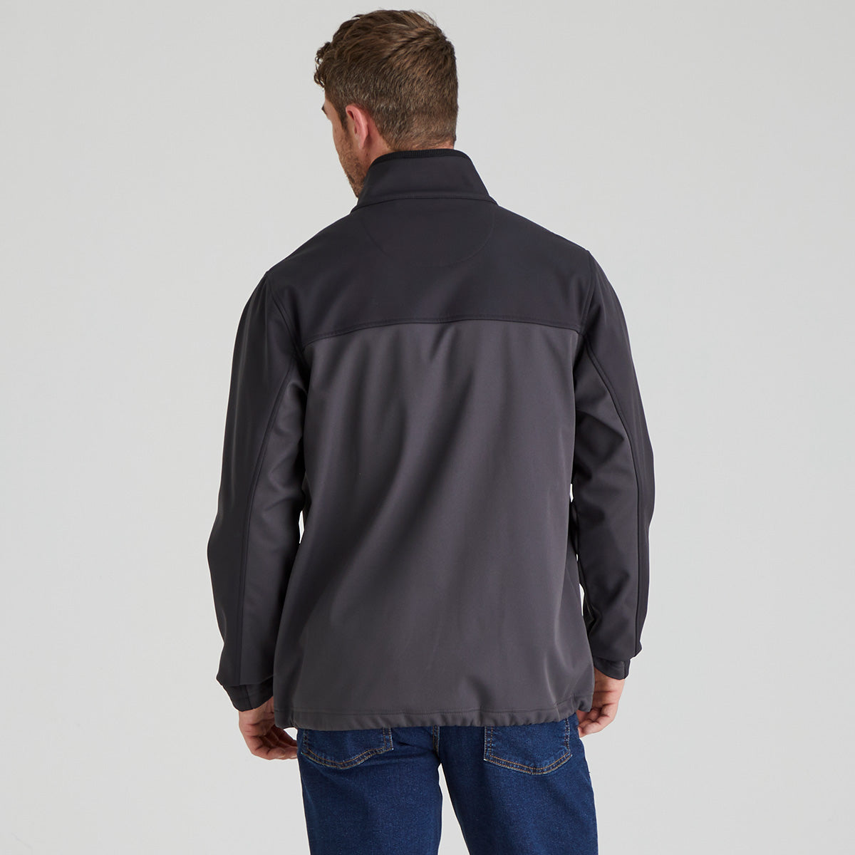back view of man wearing a two-tone jacket with a grey back and black sleeves on a light grey background
