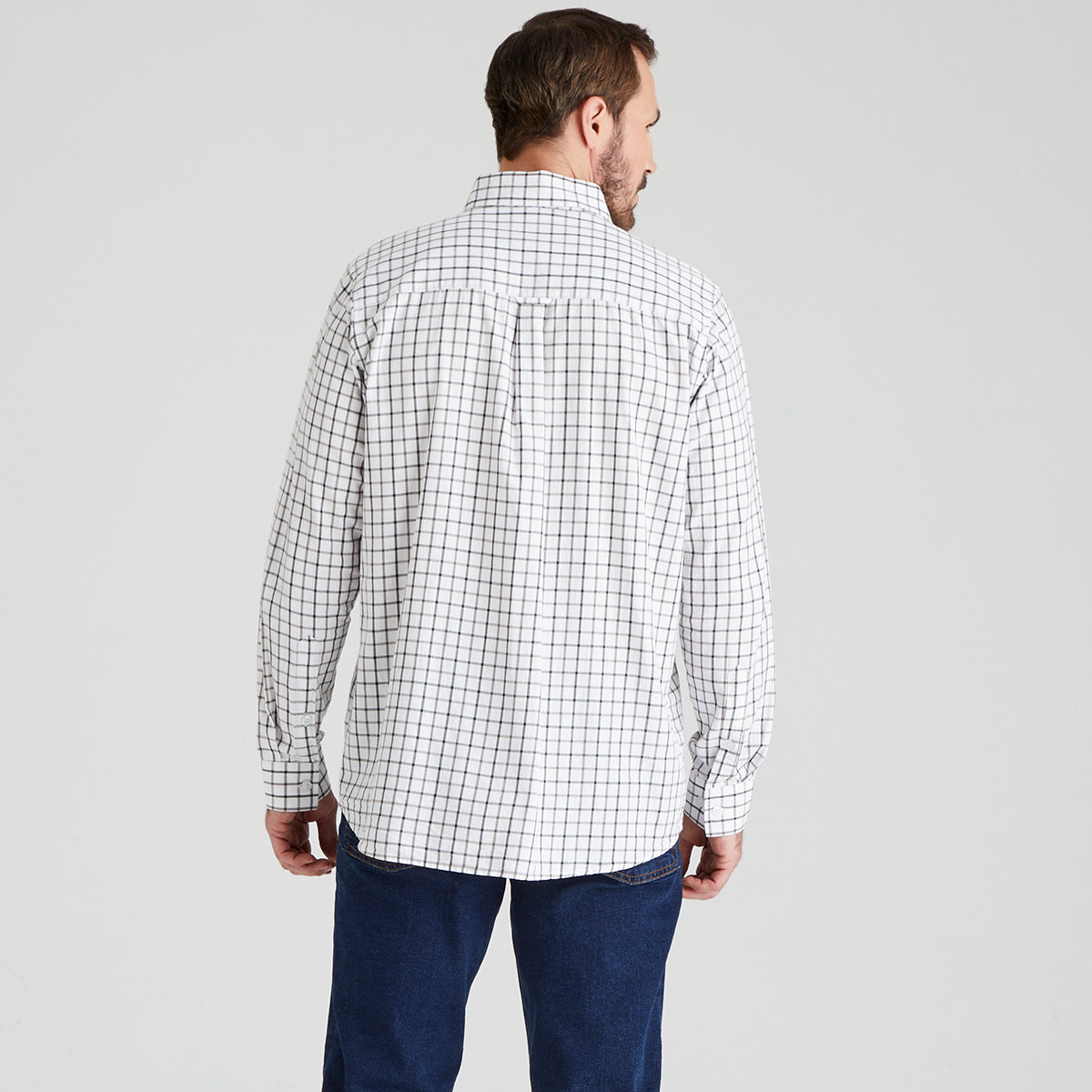 Man wearing a checkered shirt and jeans on a grey background