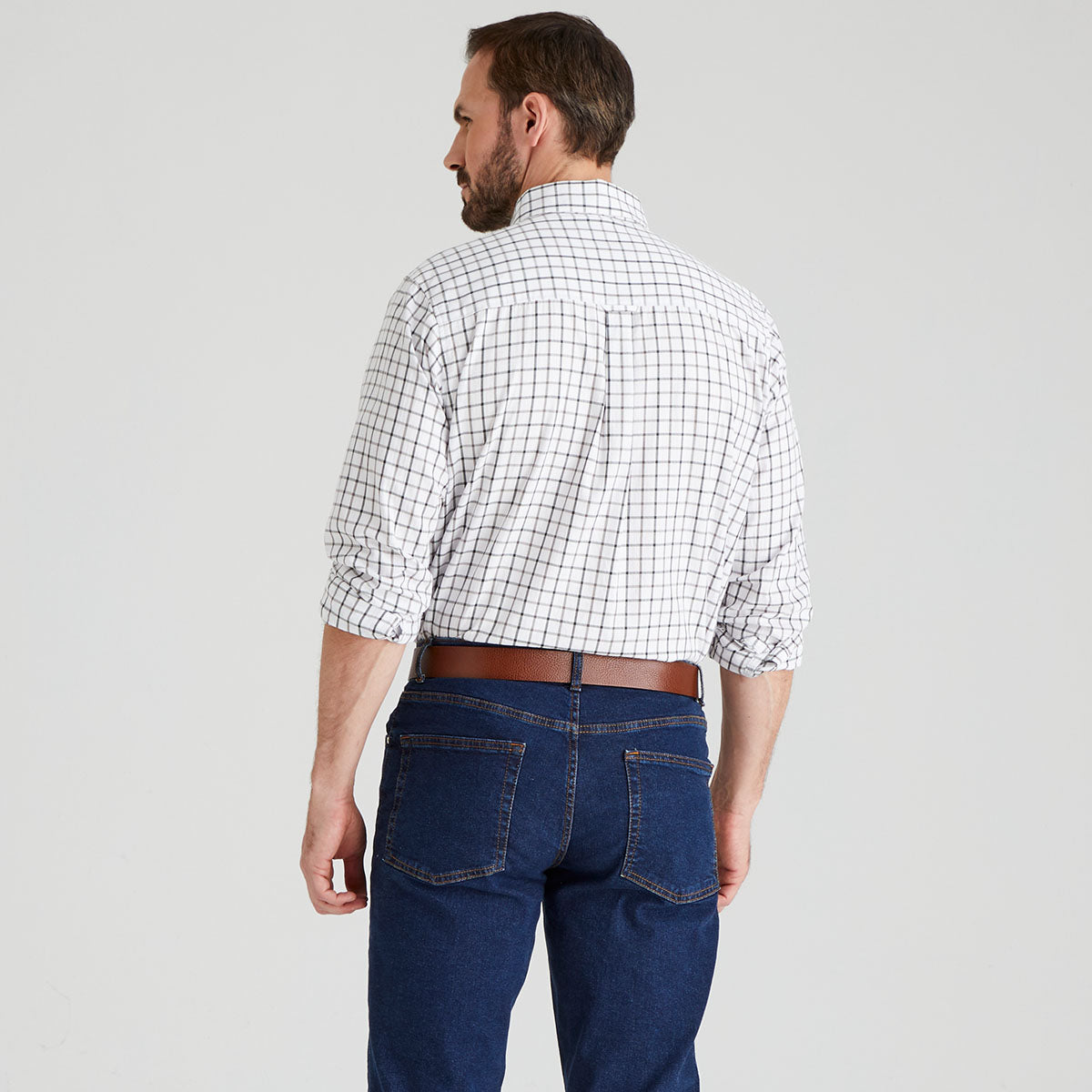 Man wearing a checkered shirt and blue jeans on a grey background