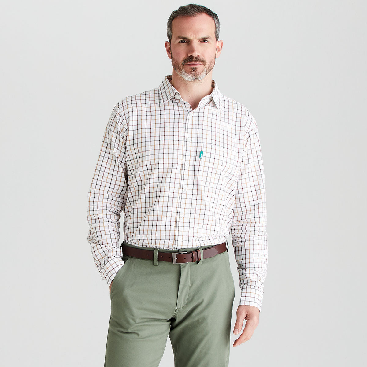 Man wearing a checkered shirt and green pants on a gray background