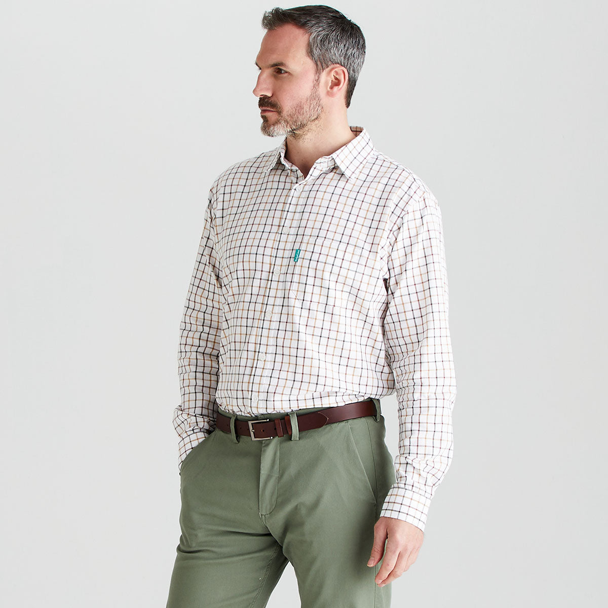 Man wearing a checkered shirt and green pants on a light gray background