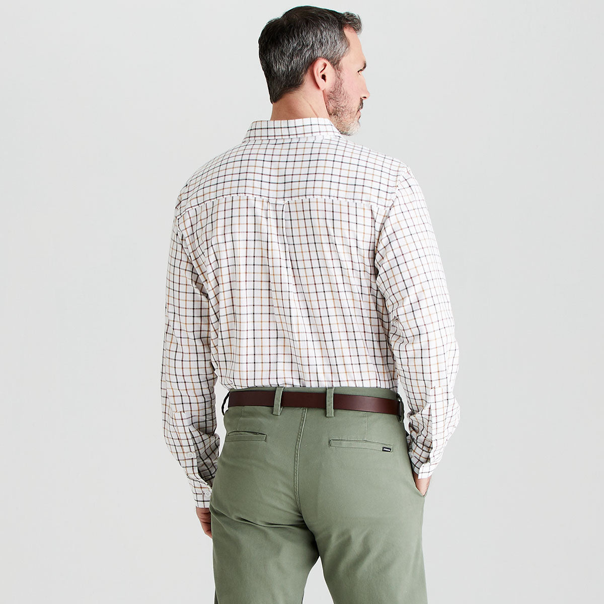 Man wearing a checkered shirt and green pants on a light gray background