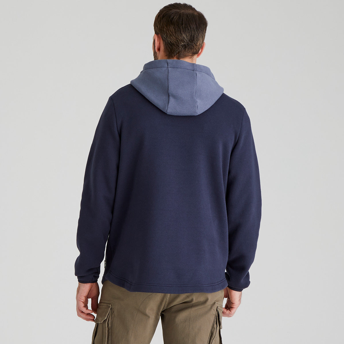 back view of Person wearing a navy blue hoodie with a light blue hood hood on a light grey background