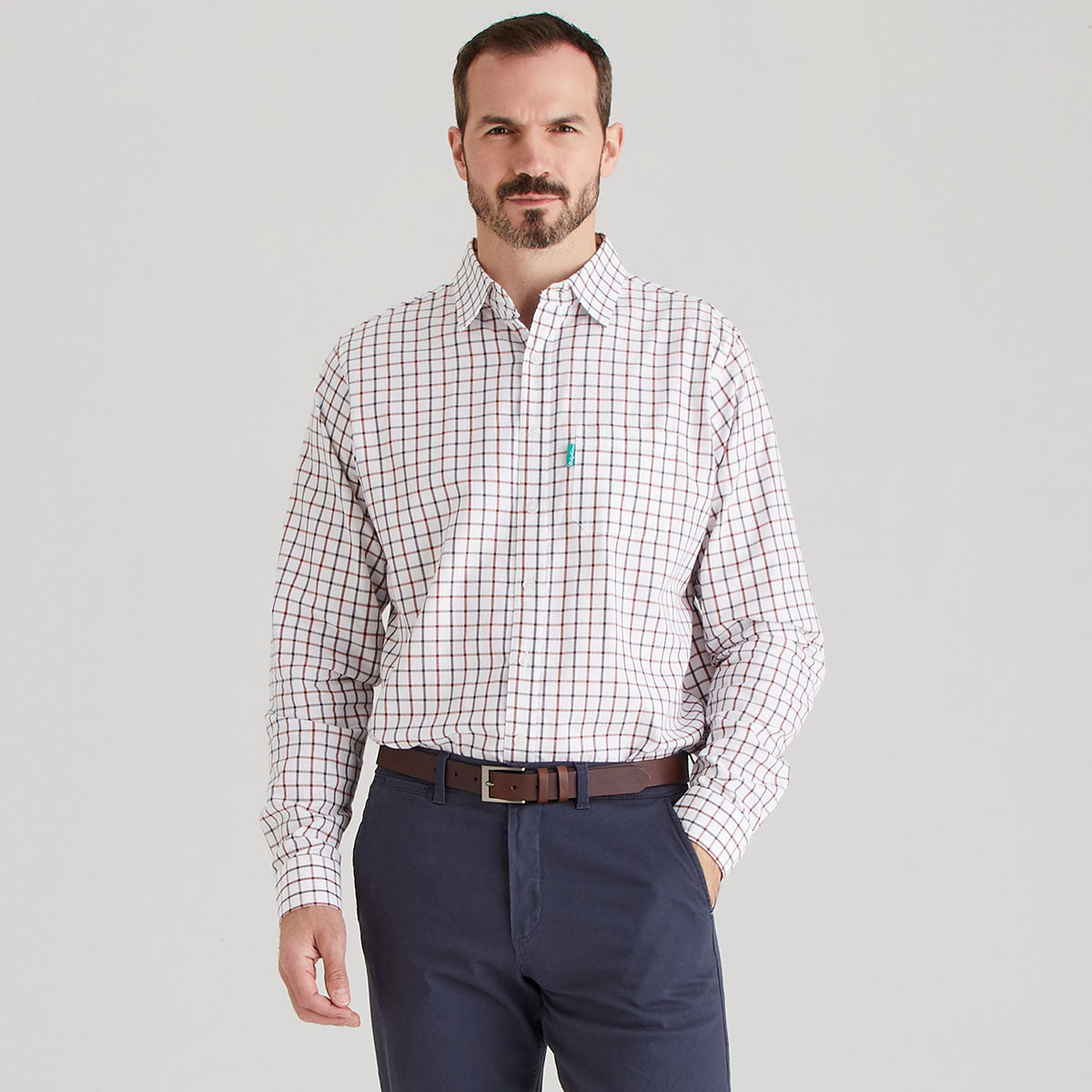 Man wearing a checkered shirt and navy pants on a gray background