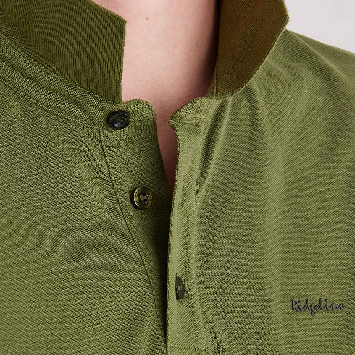 Close-up of a green polo shirt with buttons and 'Ridgeline' branding.
