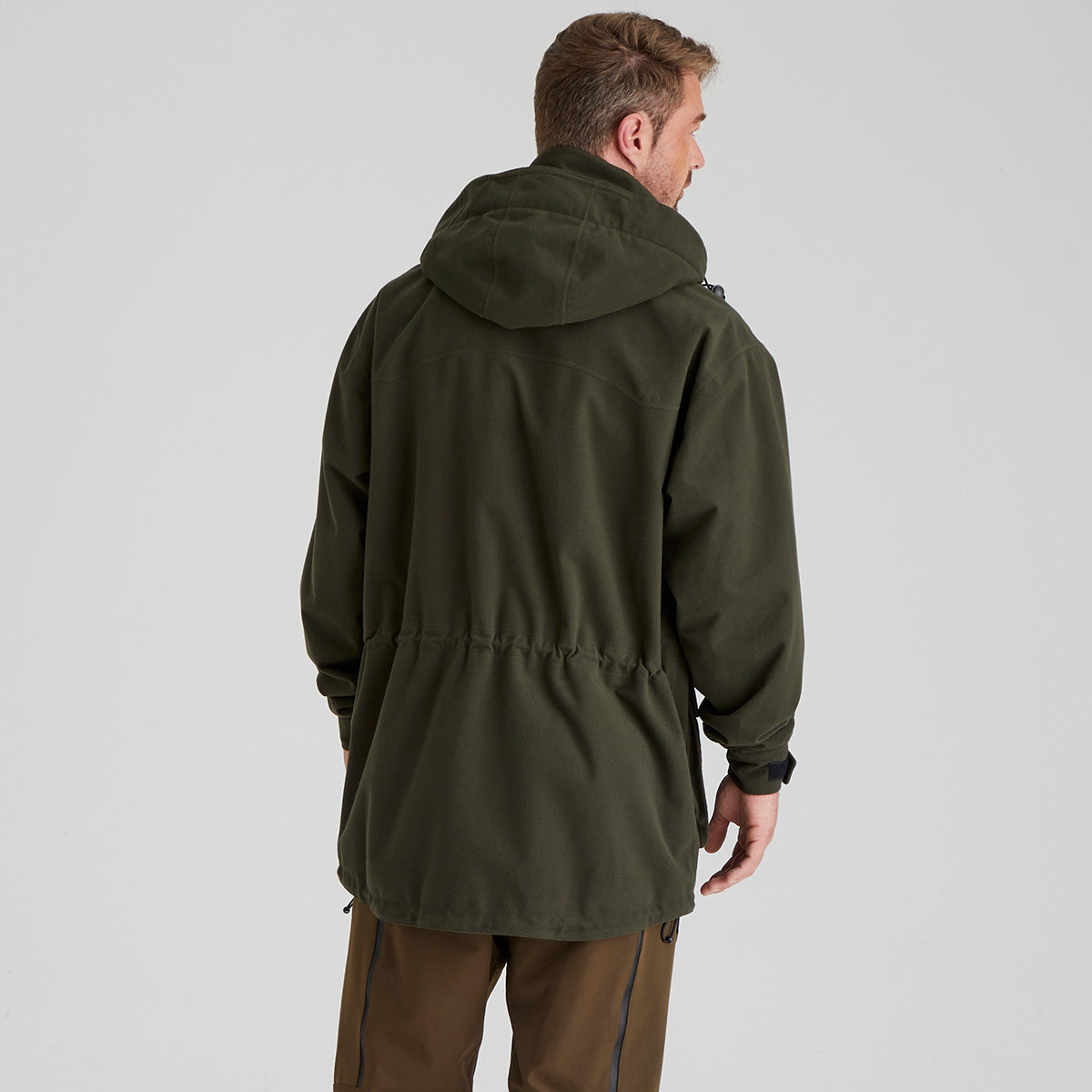 Man wearing a green waterproof jacket on a light grey background