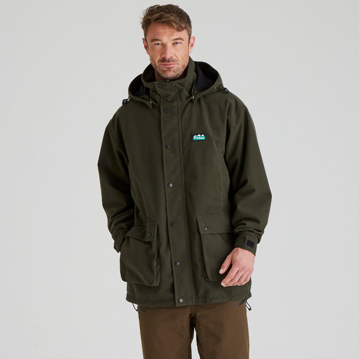Man wearing a green waterproof jacket with a Ridgeline Clothing brand logo on a grey background