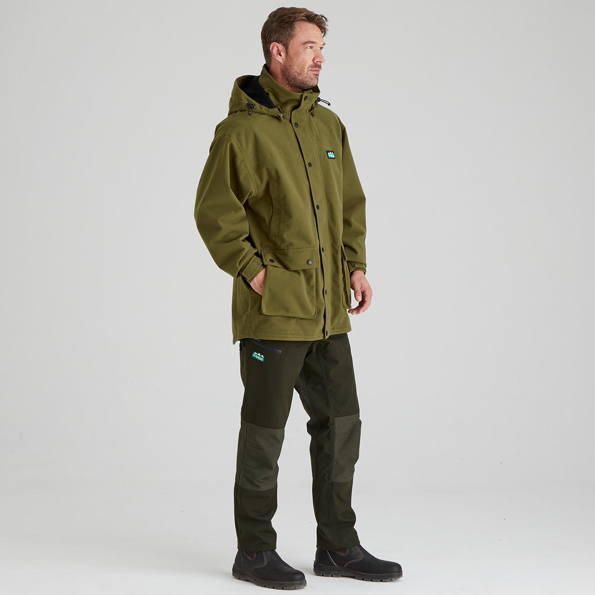 Man wearing a brown waterproof jacket with a visible Ridgeline Clothing brand logo on a grey background