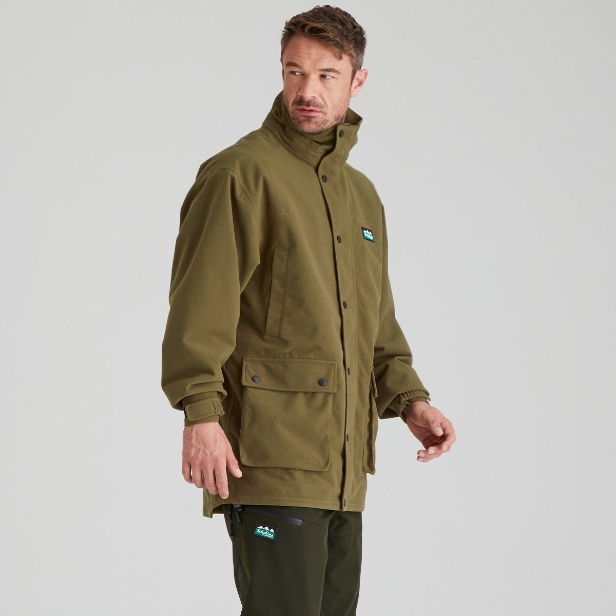 Man wearing a green jacket with a visible brand logo on a grey background