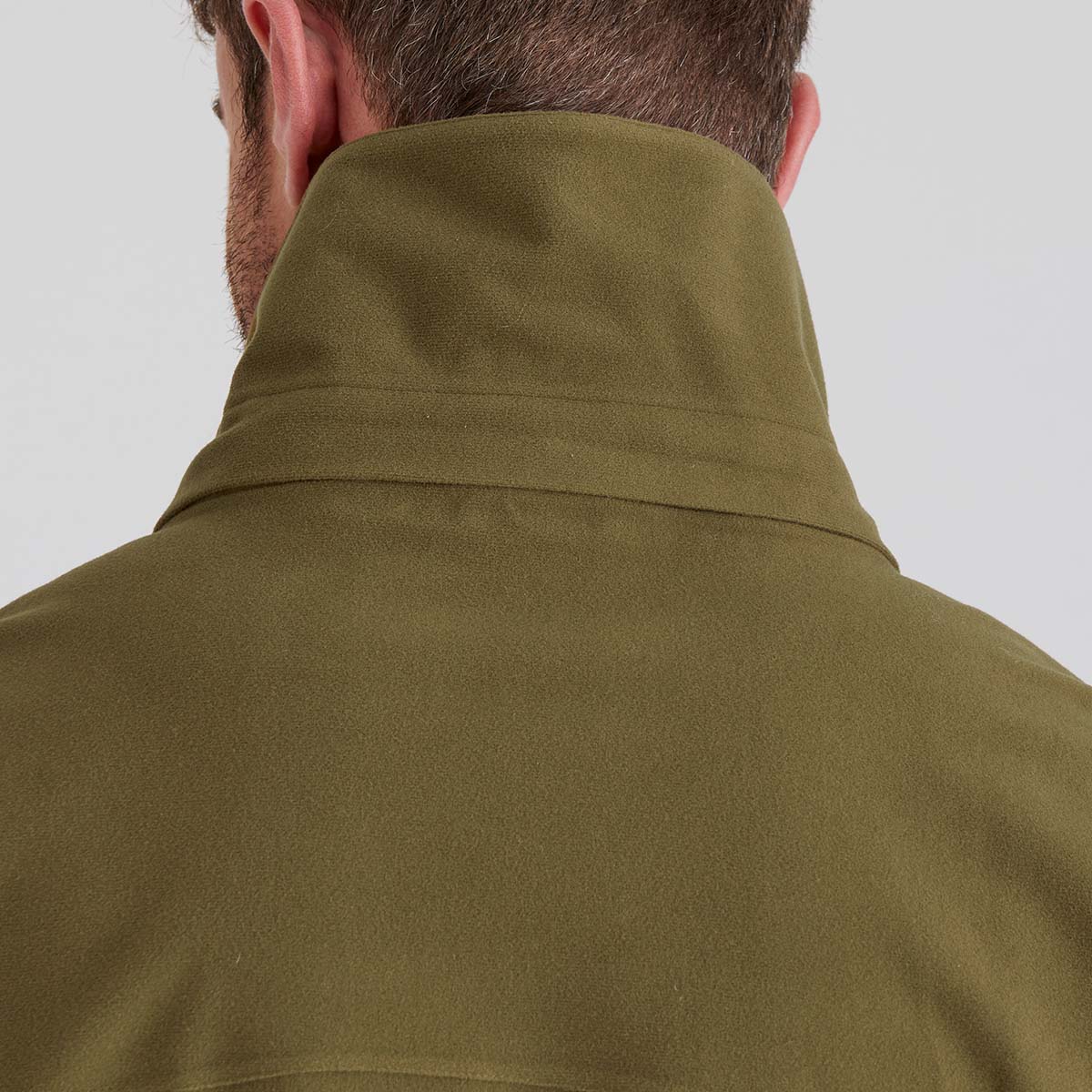 Person wearing a green jacket with a plain background