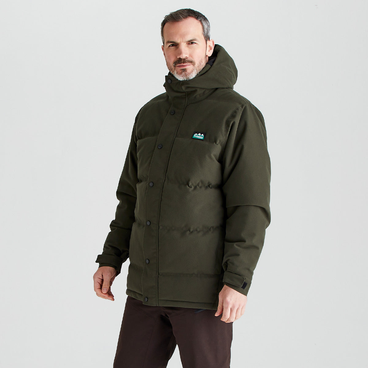 Man wearing a green jacket with a brand logo on a gray background