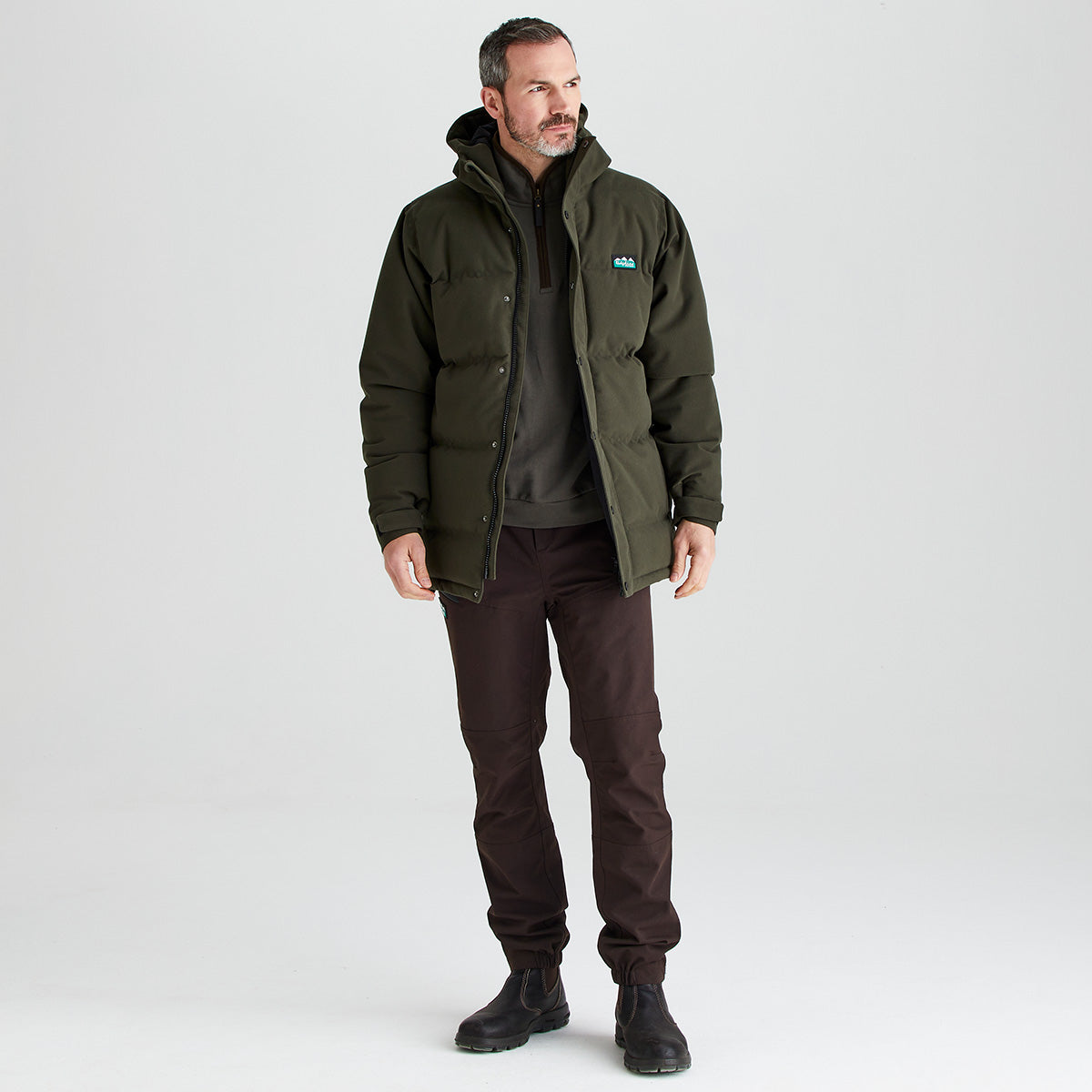 Man wearing a green jacket with a brand logo on a white background