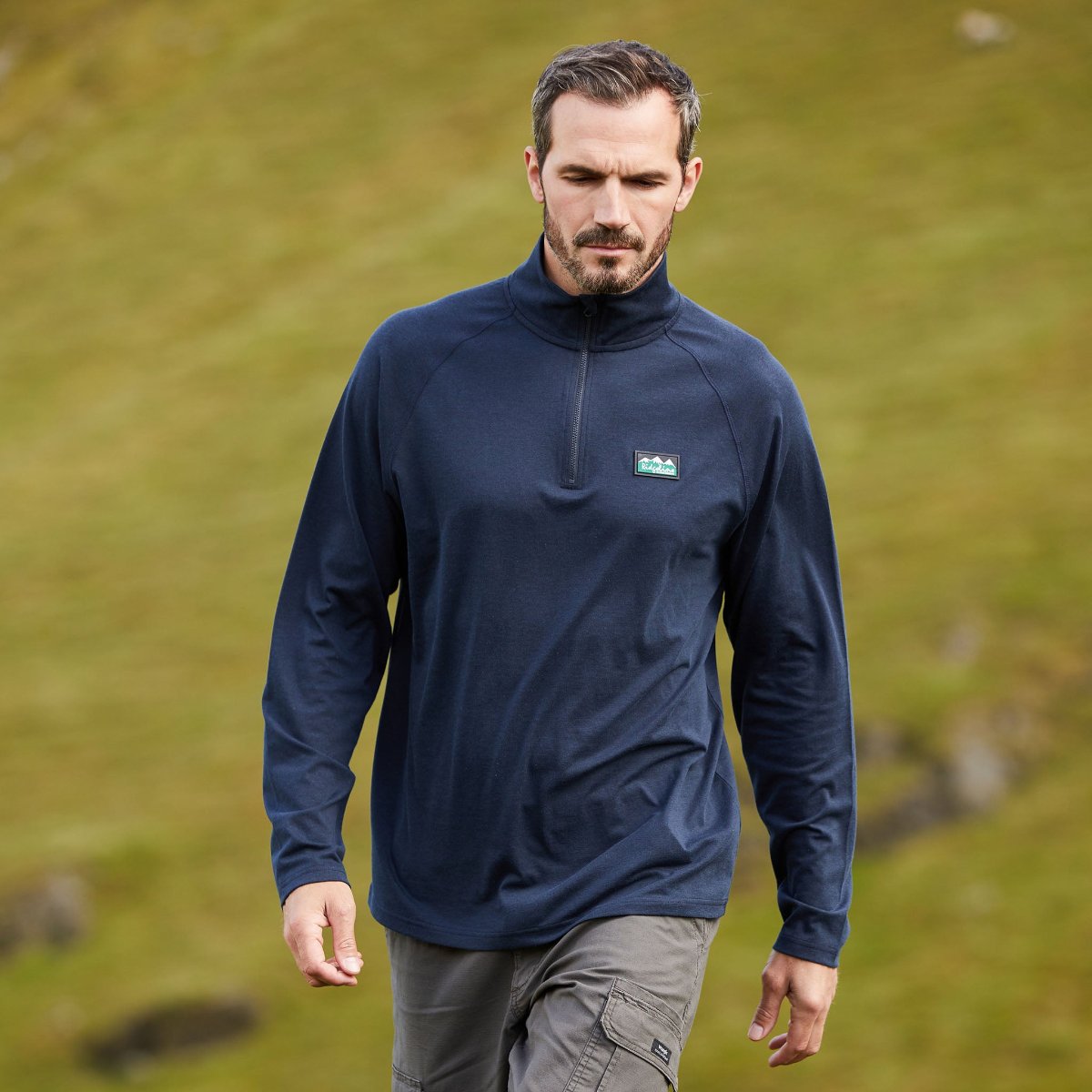 Man Wearing a navy blue zip-top fleece with a quarter zipper and raglan sleeves, displaying Ridgeline Clothing logos on chest. Walking outdoors