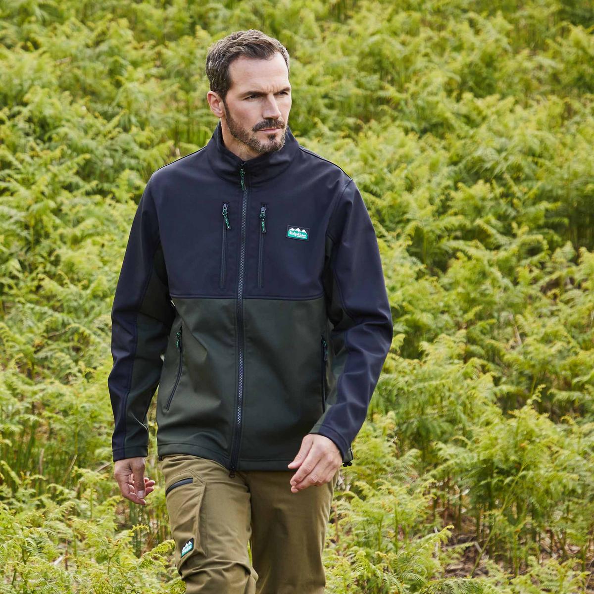 Man wearing Two-tone black and green Windproof fleece jacket with a Ridgeline Clothing logo with plants in the background