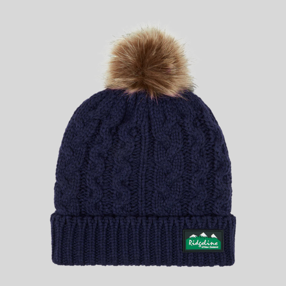 Navy blue knit beanie with brown pom-pom and Ridgeline logo on a white background