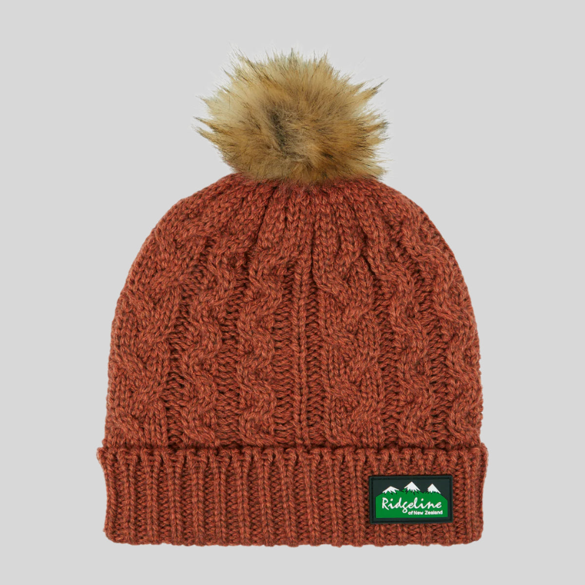 Orange knit beanie with fur pom-pom and Ridgeline logo on a white background