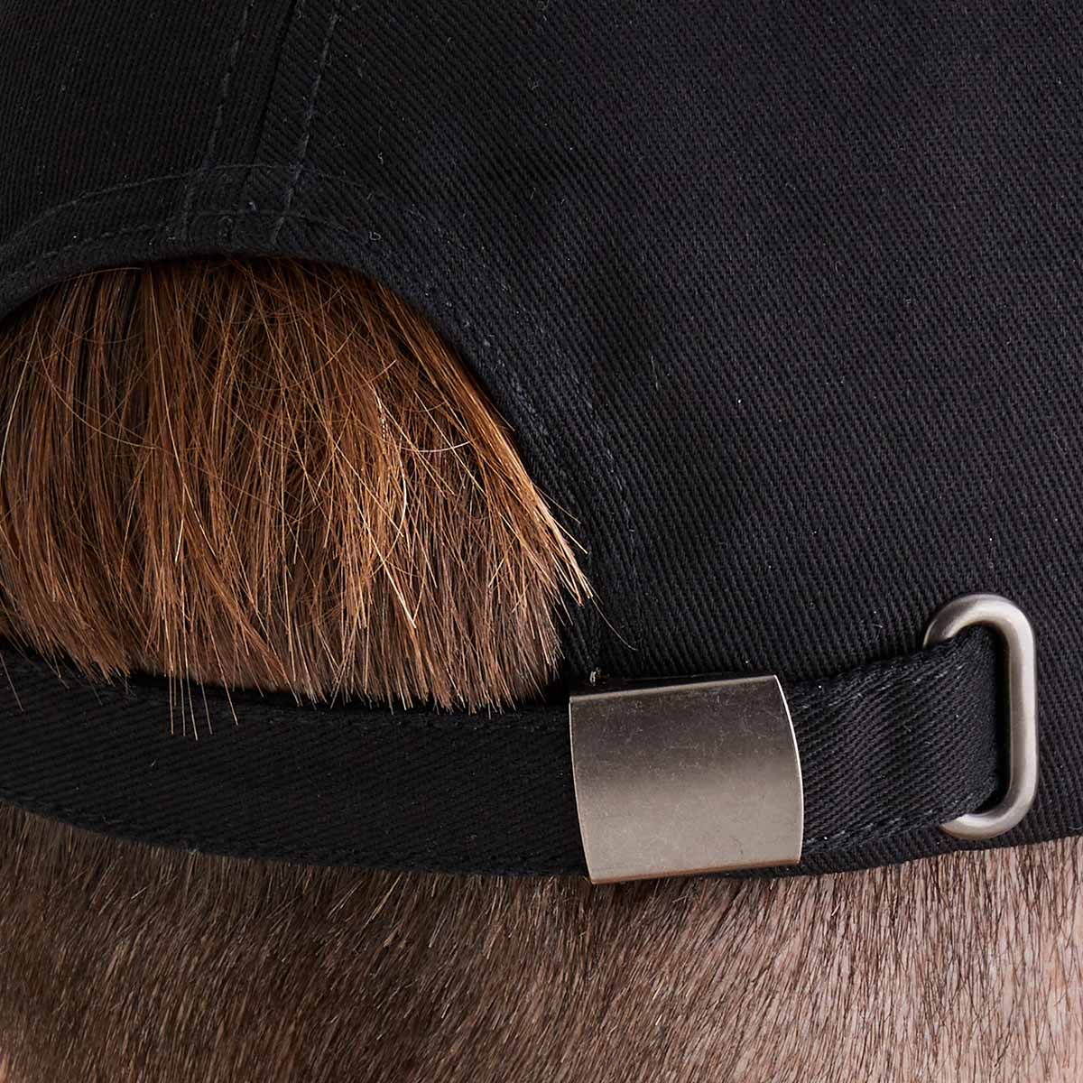 Close-up of a black cap with a metal buckle on a male model