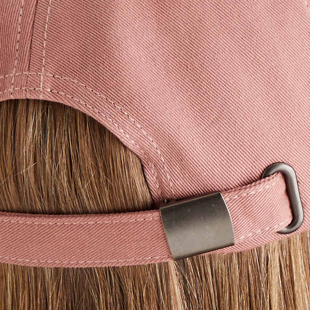 Close-up of a pink cap with a brown hair, showing the strap and buckle.