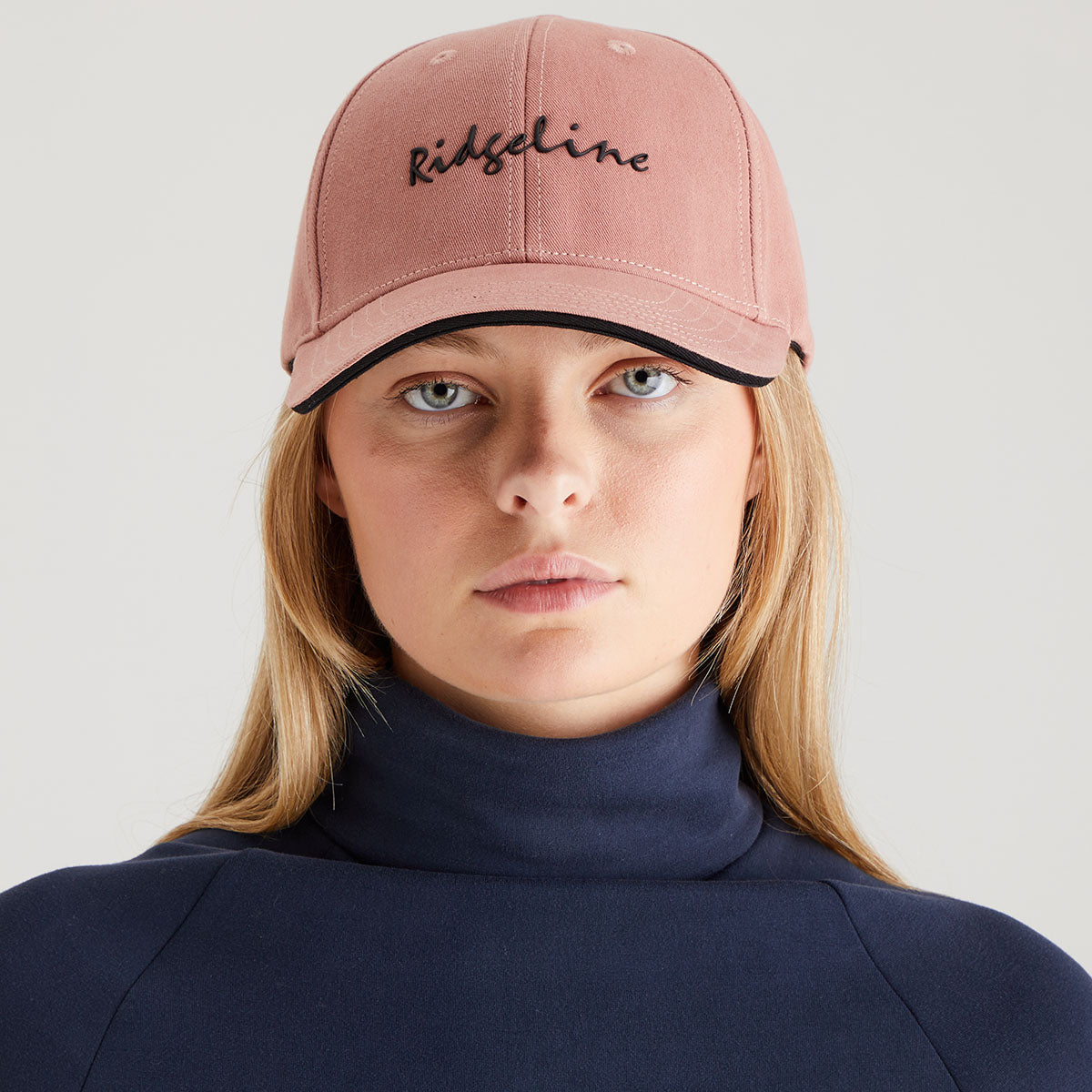 Person wearing a pink cap with 'Ridgeline' branding on a plain background