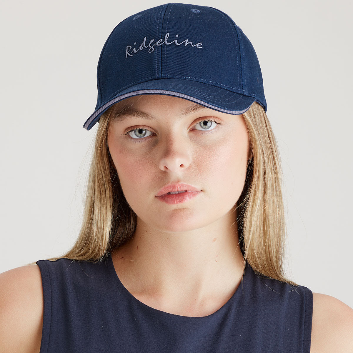 Person wearing a navy blue cap with 'Ridgeline' embroidered on it against a plain background