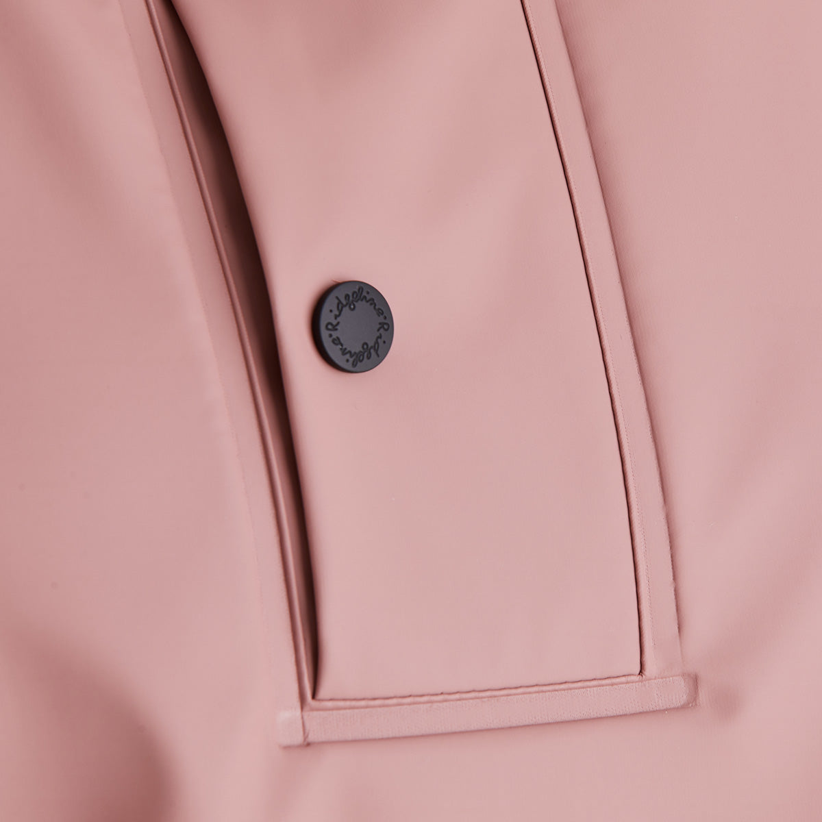 Close-up of a pink garment with a button featuring a brand logo.