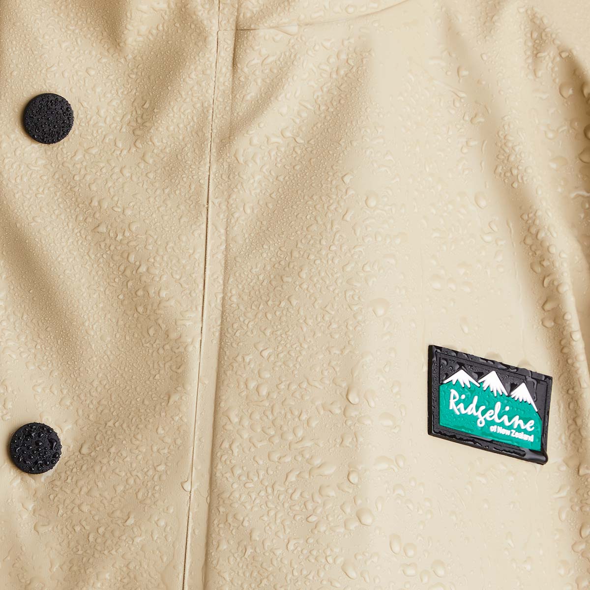 Close-up of a beige textured jacket with a Ridgeline logo patch.