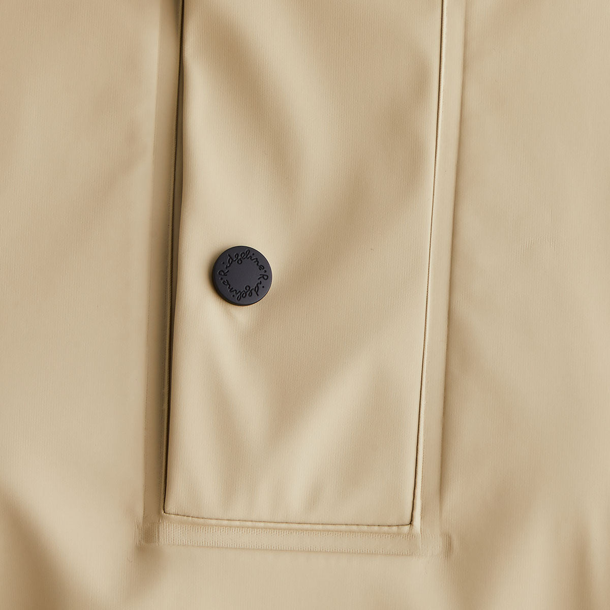 Close-up of a beige jacket with a button on a beige background