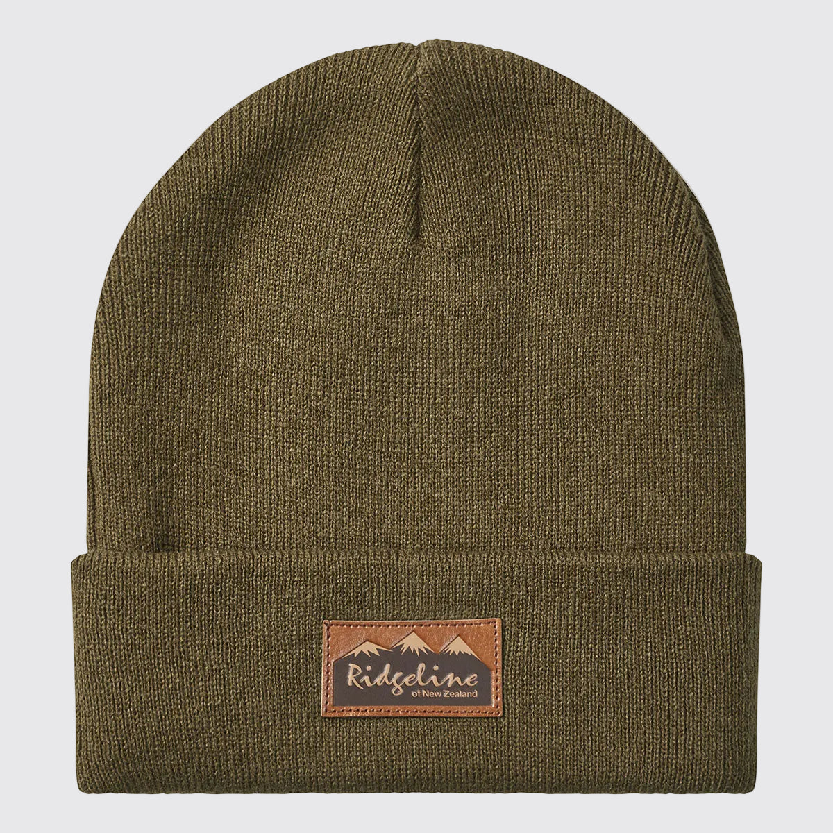Front view of a greenish-brown ribbed knit beanie with a folded cuff, displayed against a light grey background. A brown faux-leather patch is centered on the cuff, featuring the Ridgeline of New Zealand logo with a mountain graphic. The fine-knit texture, stretch-fit construction, and classic cuffed design are clearly visible, highlighting the beanie's warm, durable, and versatile outdoor style.