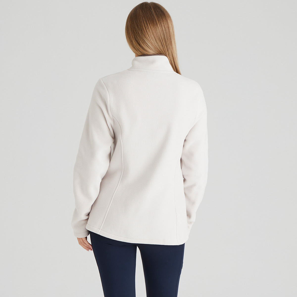 back view of Person wearing a light cream jacket on a plain background