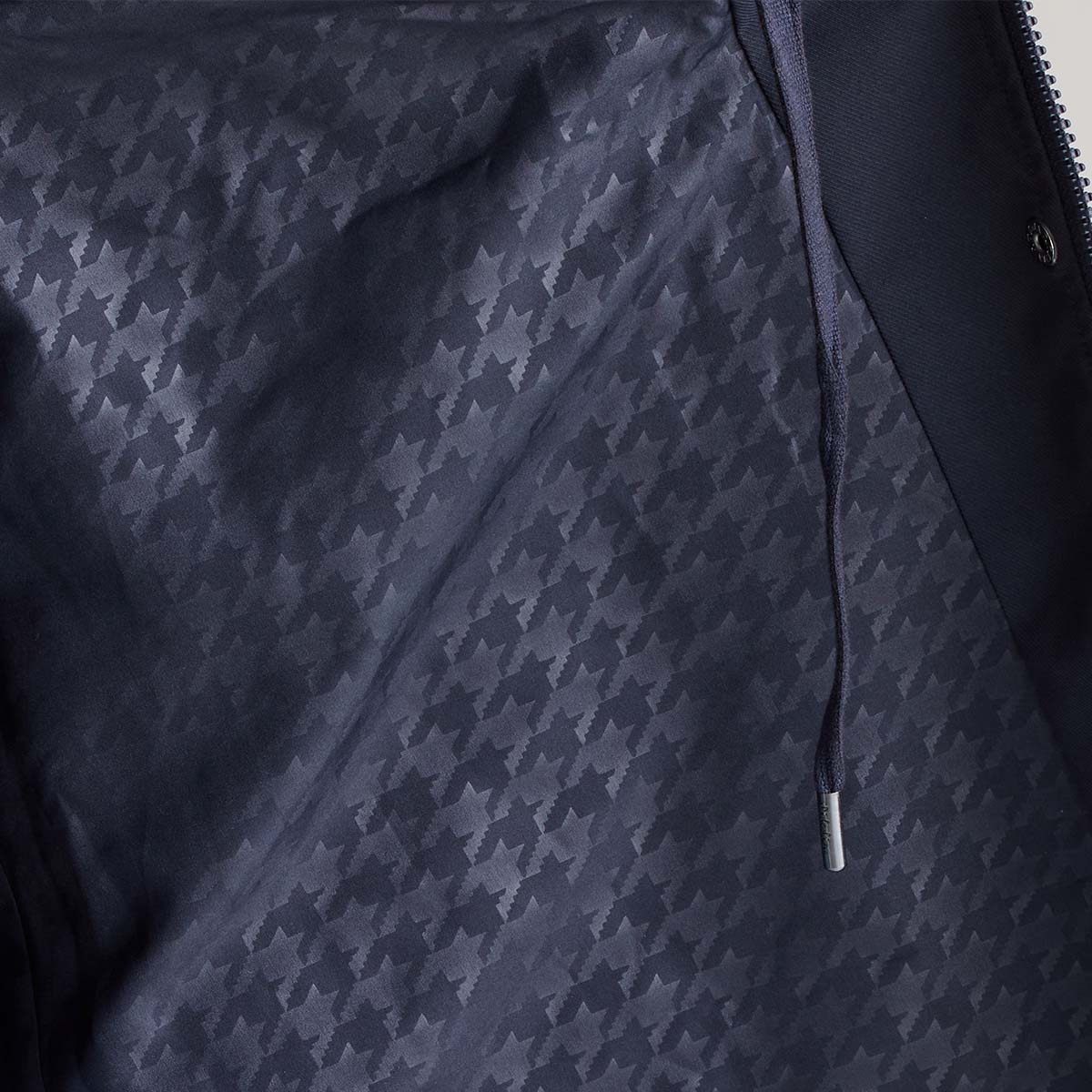 Close-up of a navy jacket with a houndstooth pattern on a neutral background
