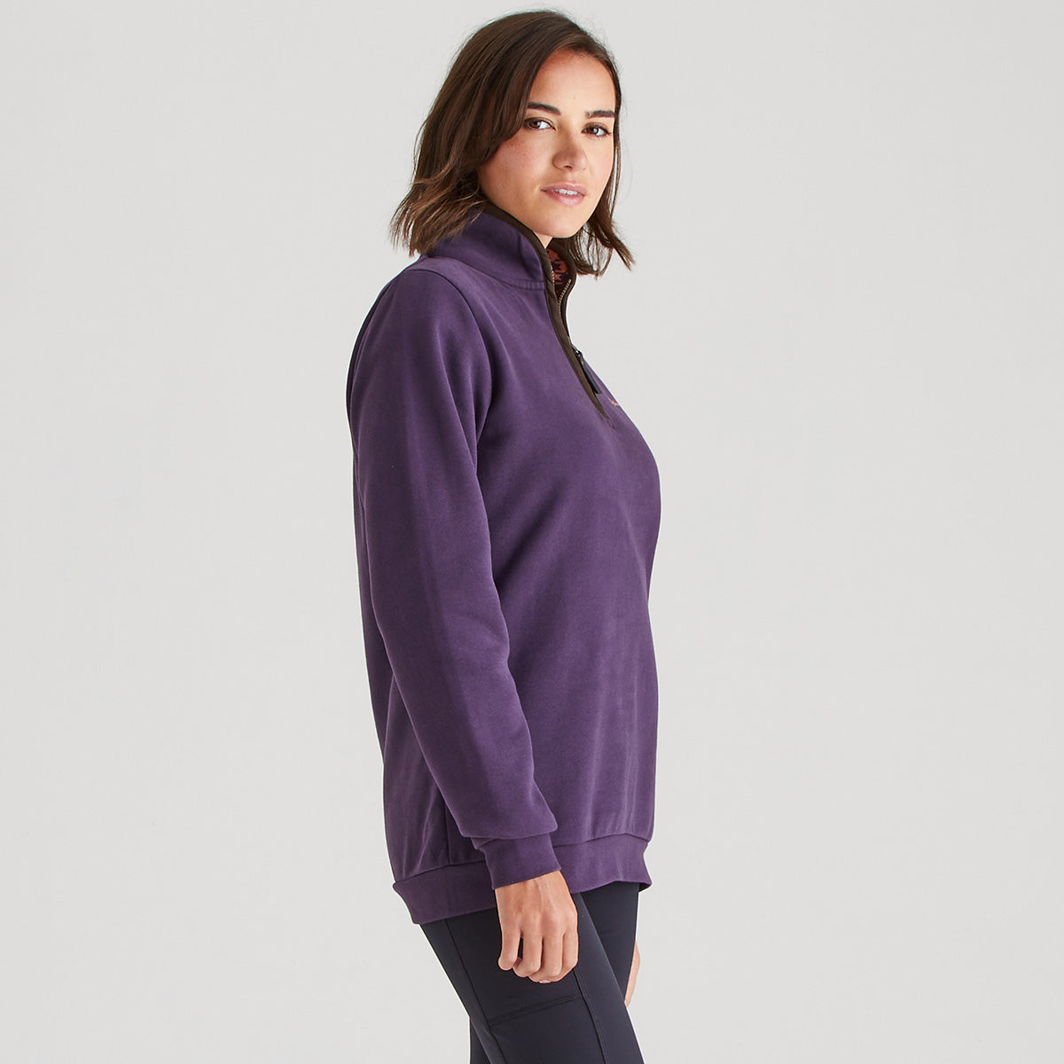 Woman wearing a purple zip-up sweatshirt on a light gray background