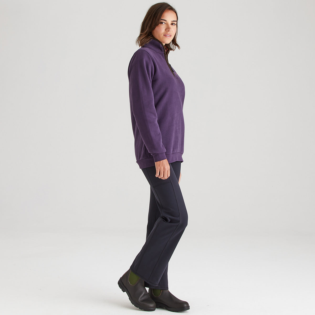 Person wearing a purple sweater and dark pants on a white background