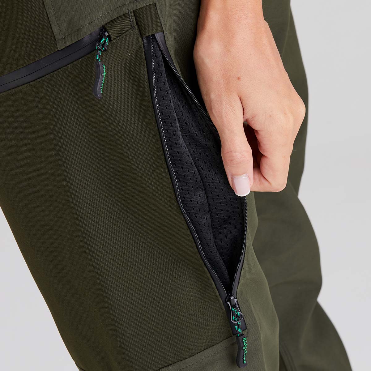 Person opening a green zipper with a hand on a light grey background