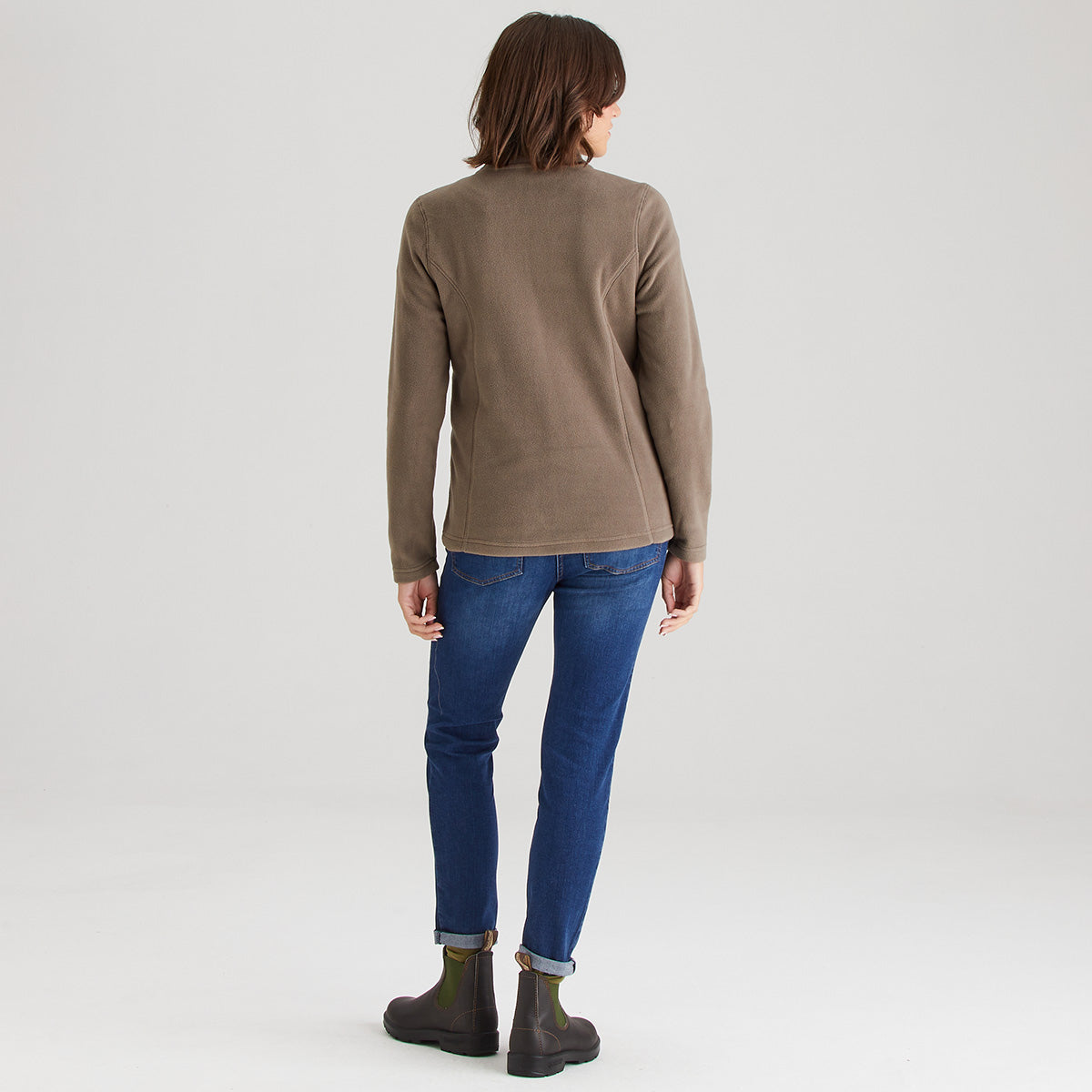 Person wearing a brown sweater and blue jeans on a white background