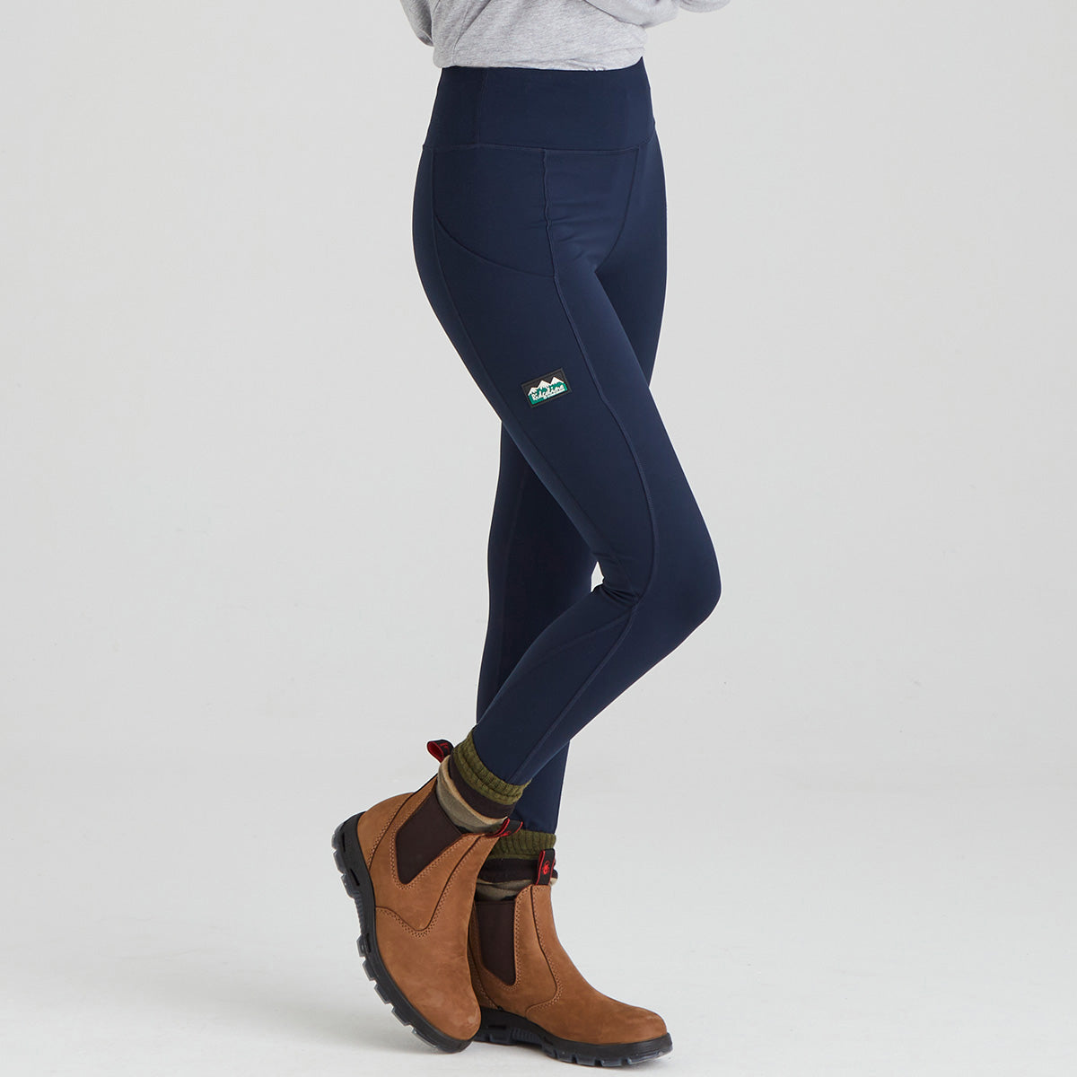 Navy leggings with a ridgeline clothing brand logo worn by a person on a light grey background