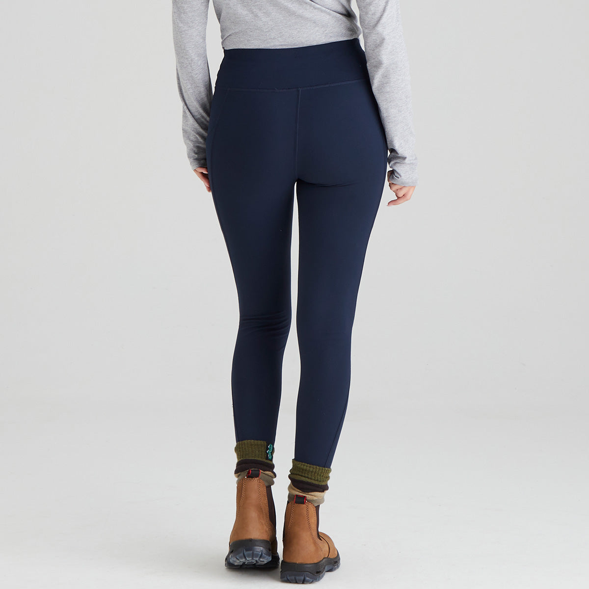back view of person wearing navy leggings with a plain background