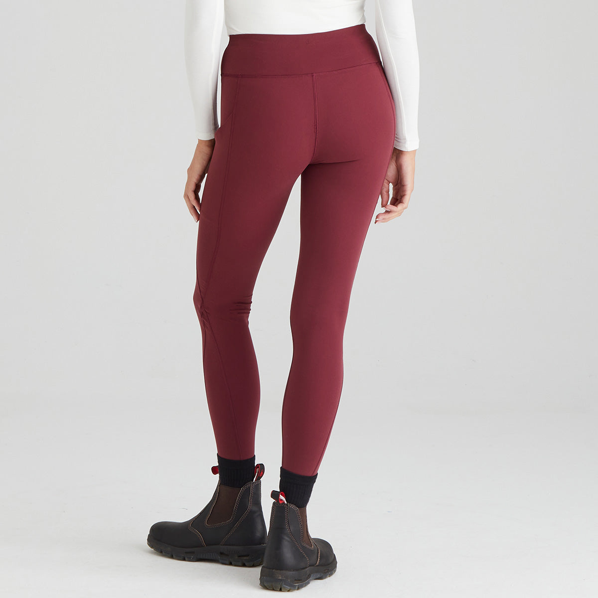 back view of maroon leggings worn by a person on a white background