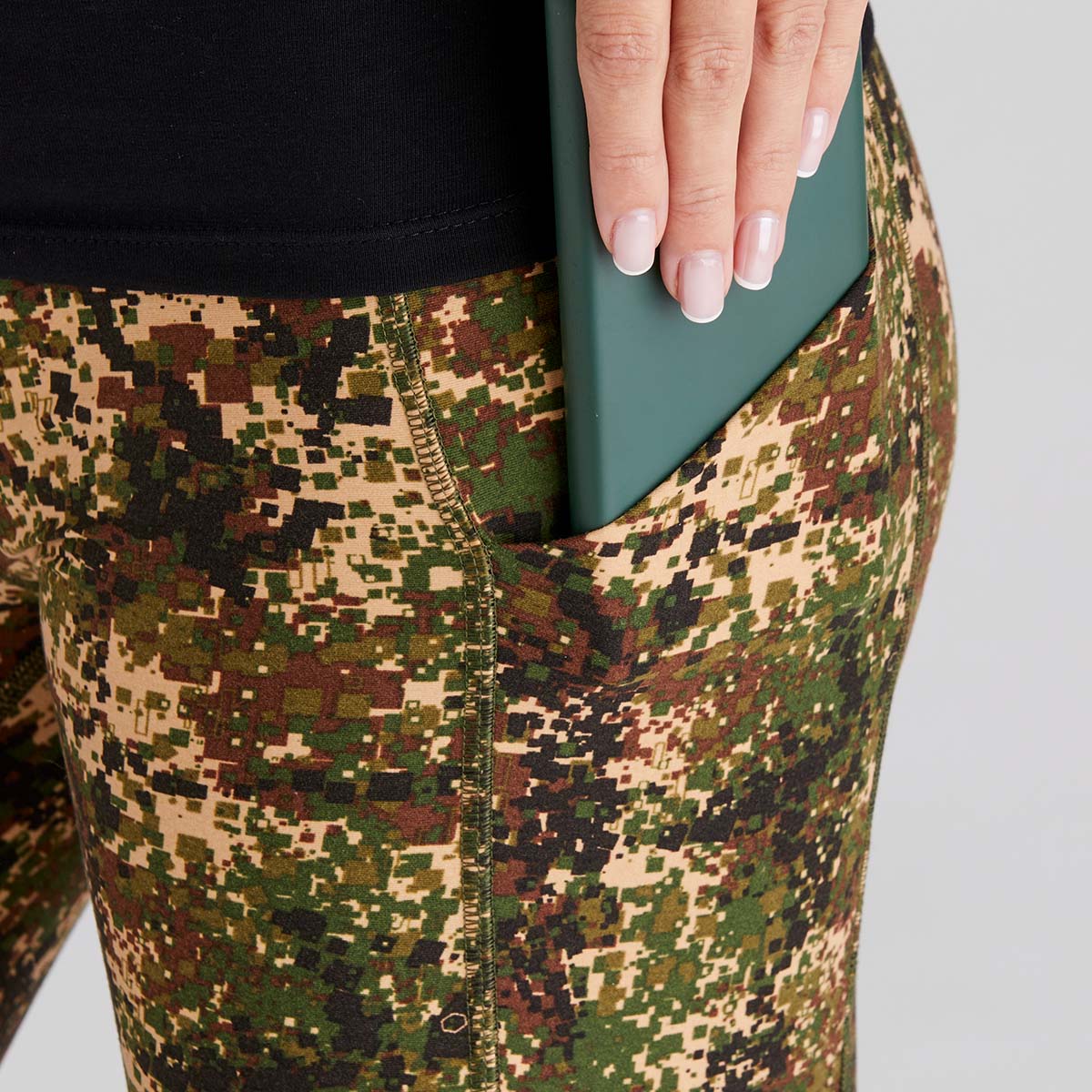 Camouflage pants with a hand holding a green phone case.