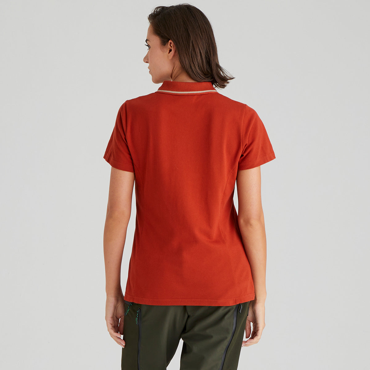 back view of person wearing a orange polo shirt on a plain background